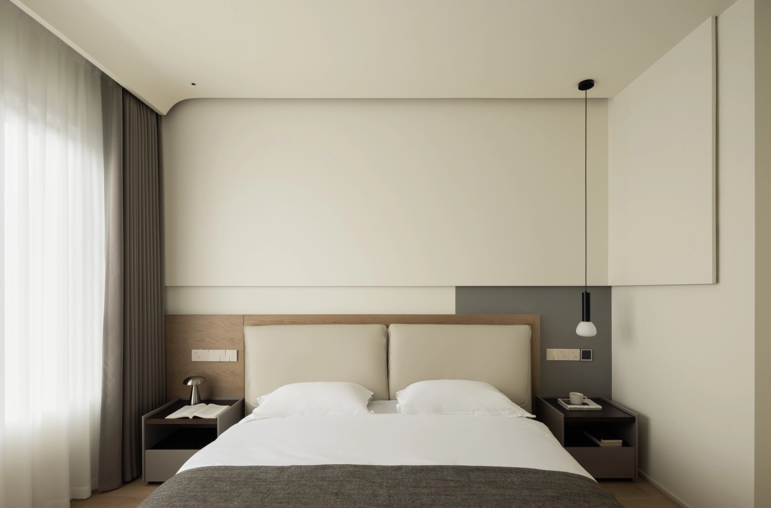Minimalist bedroom with curved headboard, soft lighting, and earth-tone textiles.
