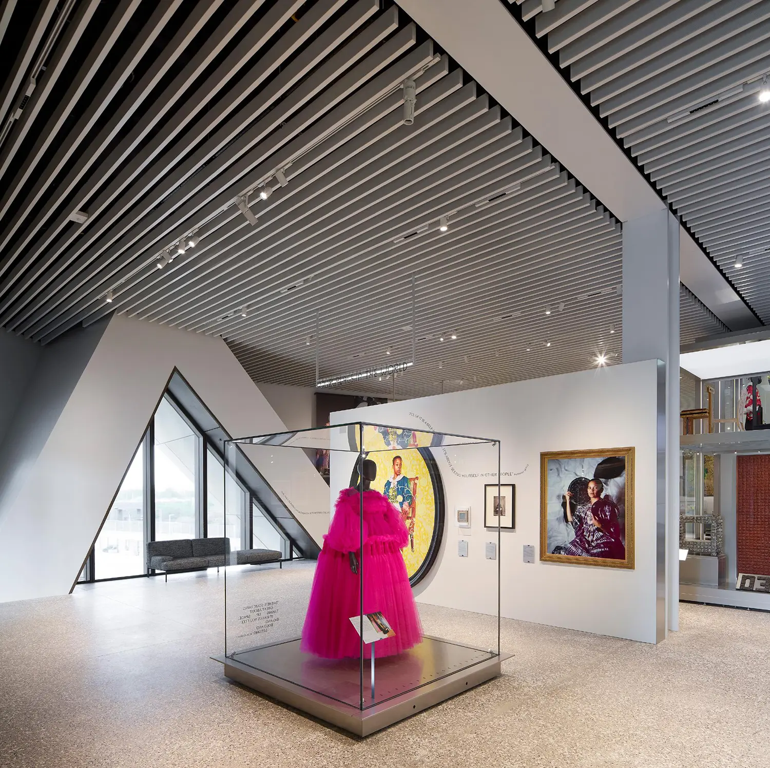 Gallery view inside V&A East Museum with a bright pink couture dress displayed in a glass case.