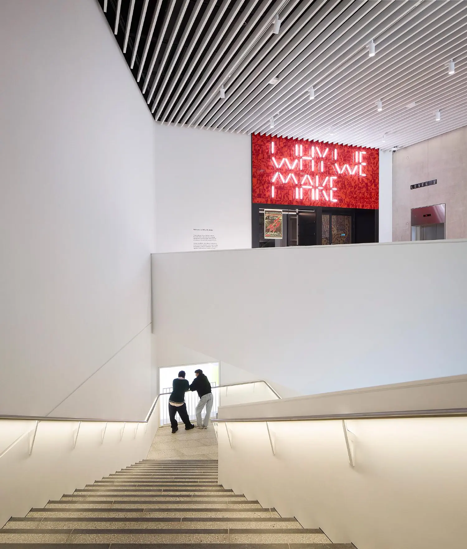 A wide white staircase inside V&A East Museum with glowing handrails and neon art.