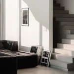 Contemporary living room showing visual weight with a black tufted sofa and a minimalist white concrete staircase under sharp natural light shadows.