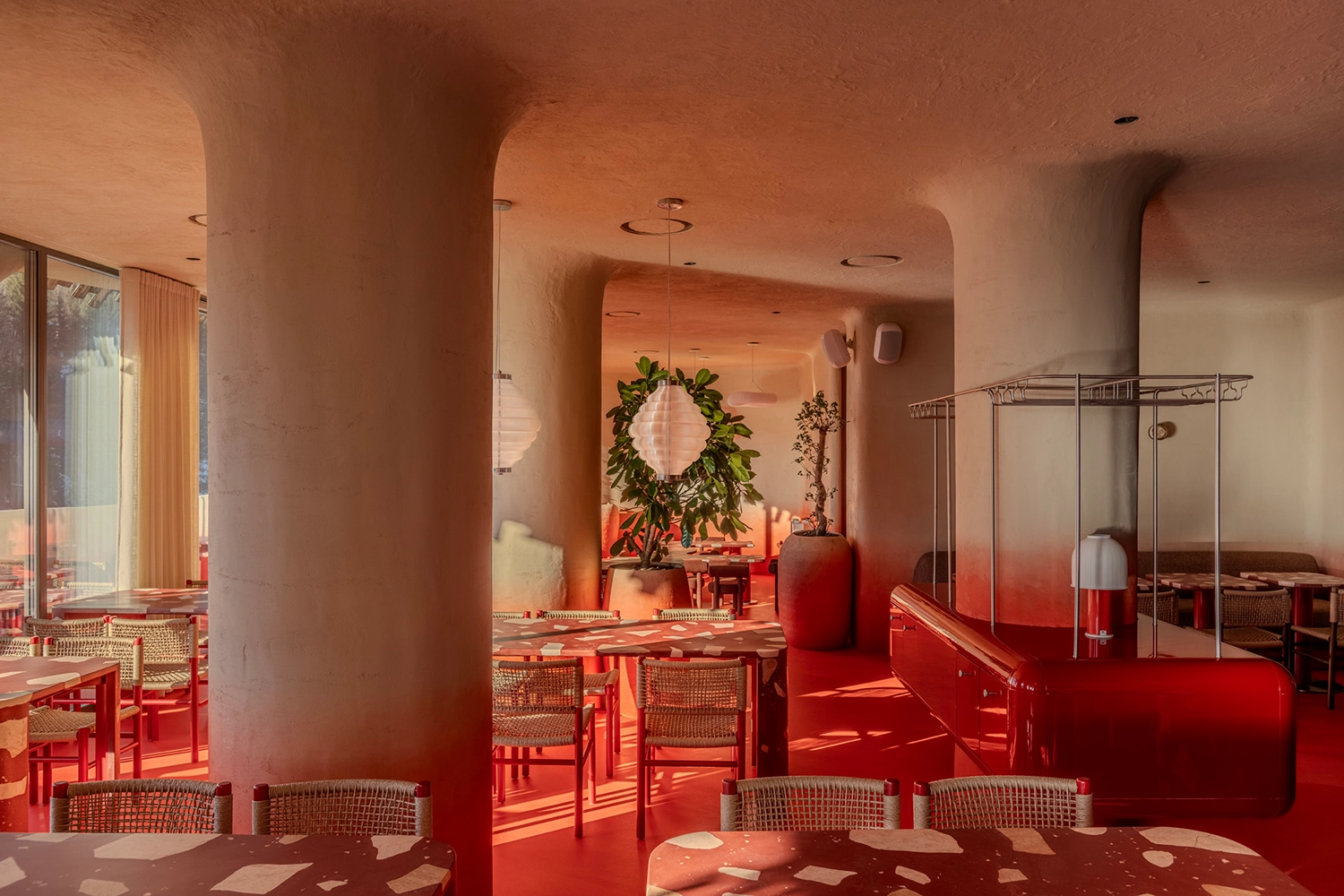 Close-up of concrete dining tables with large aggregate terrazzo tops and woven chairs at Rosso.