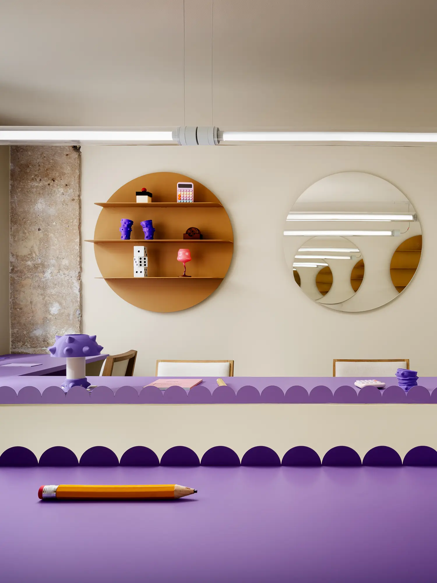 Frontal view of a mustard-yellow circular shelf holding dice and 3D-printed objects next to a round mirror.