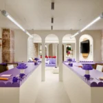 Symmetrical perspective of purple workstations and cream arches in Artus Office Paris.