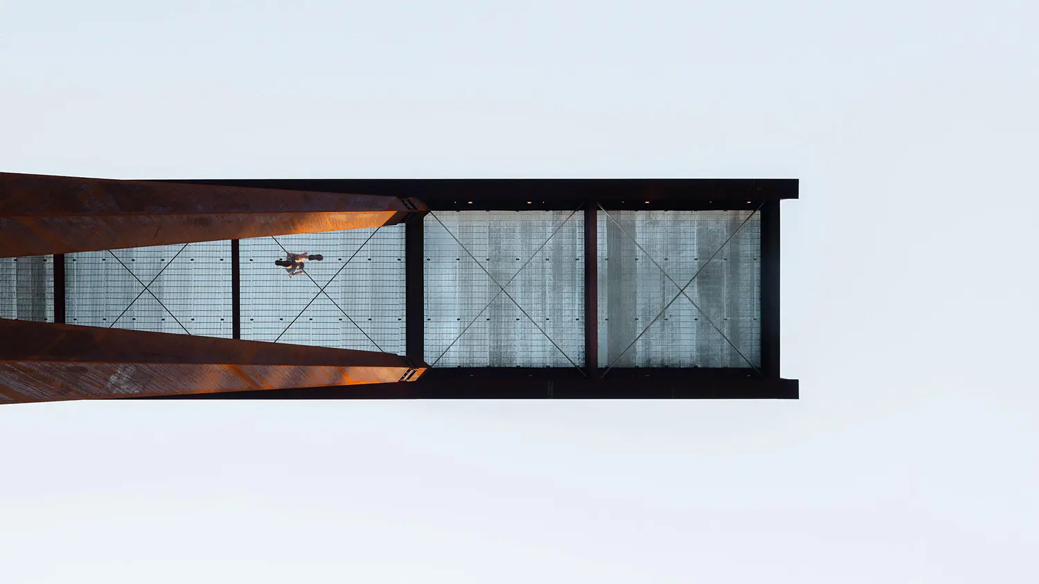 Direct upward shot from beneath the lookout showing the industrial steel structure and the transparent grated metal flooring.