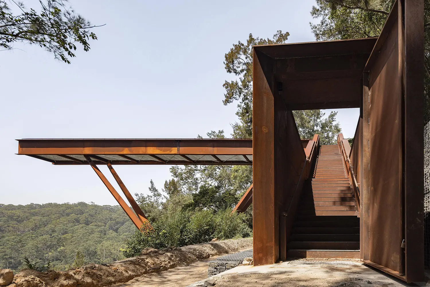 A wide weathering steel staircase leading up to the main viewing platform, framed by an industrial-style rectangular portal.