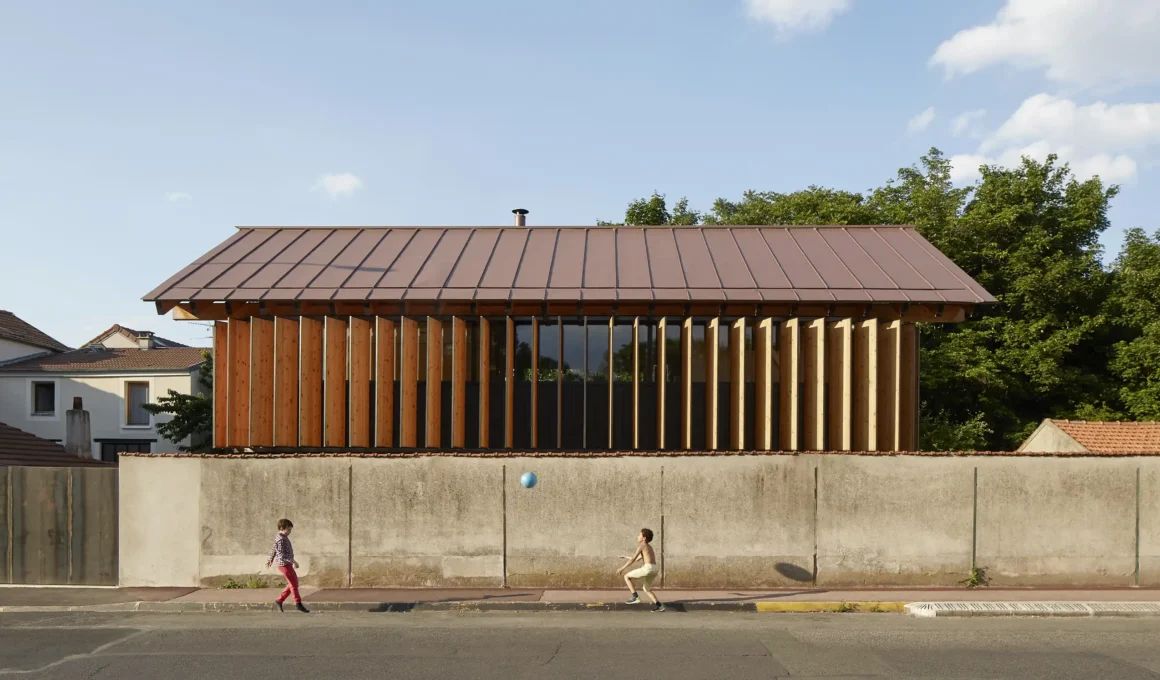 Arba Maison sur le Mur street facade with rotating larch louvers and red zinc roof in Fontenay-sous-Bois