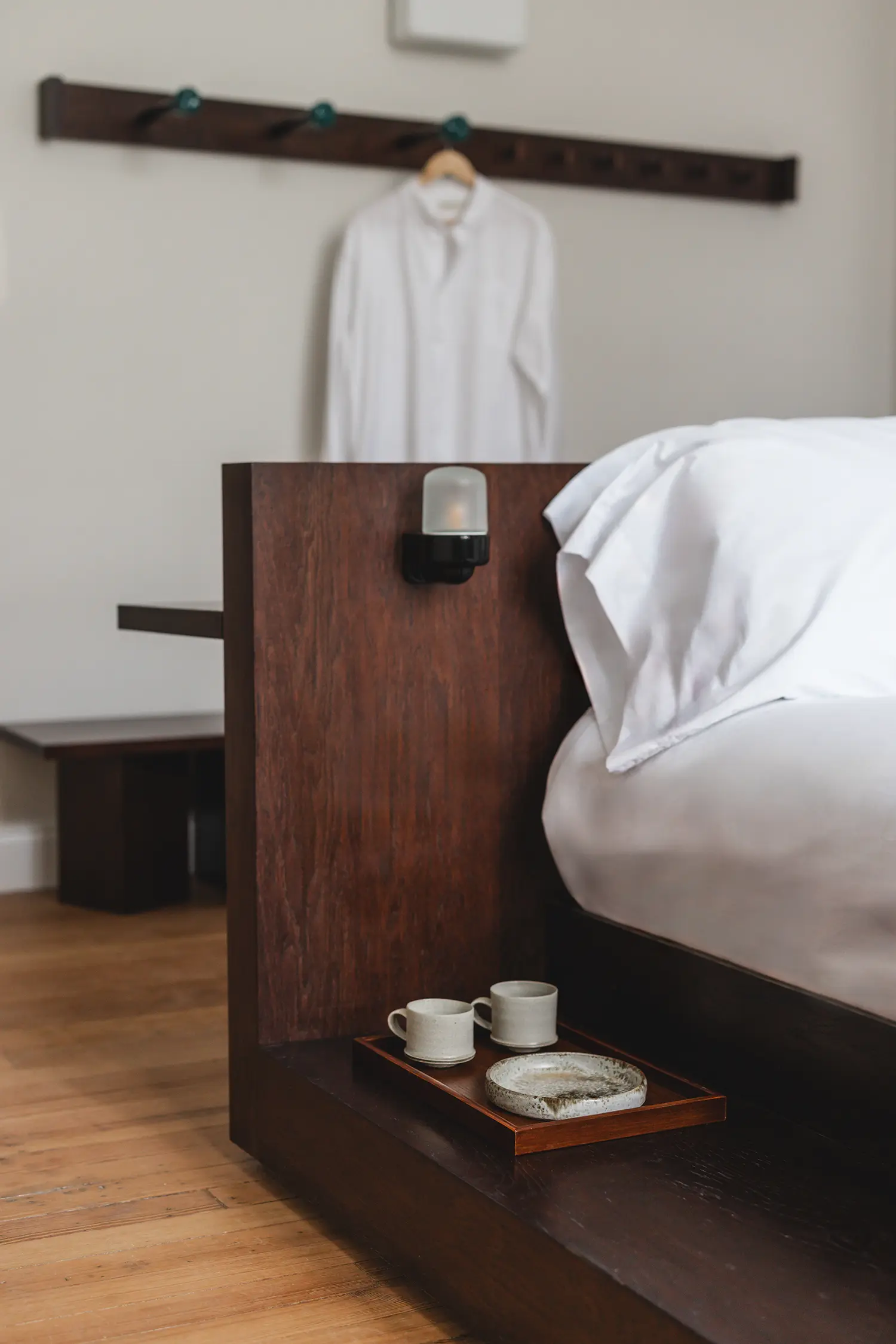 Close-up of dark timber headboard with integrated lighting and ceramic cups.