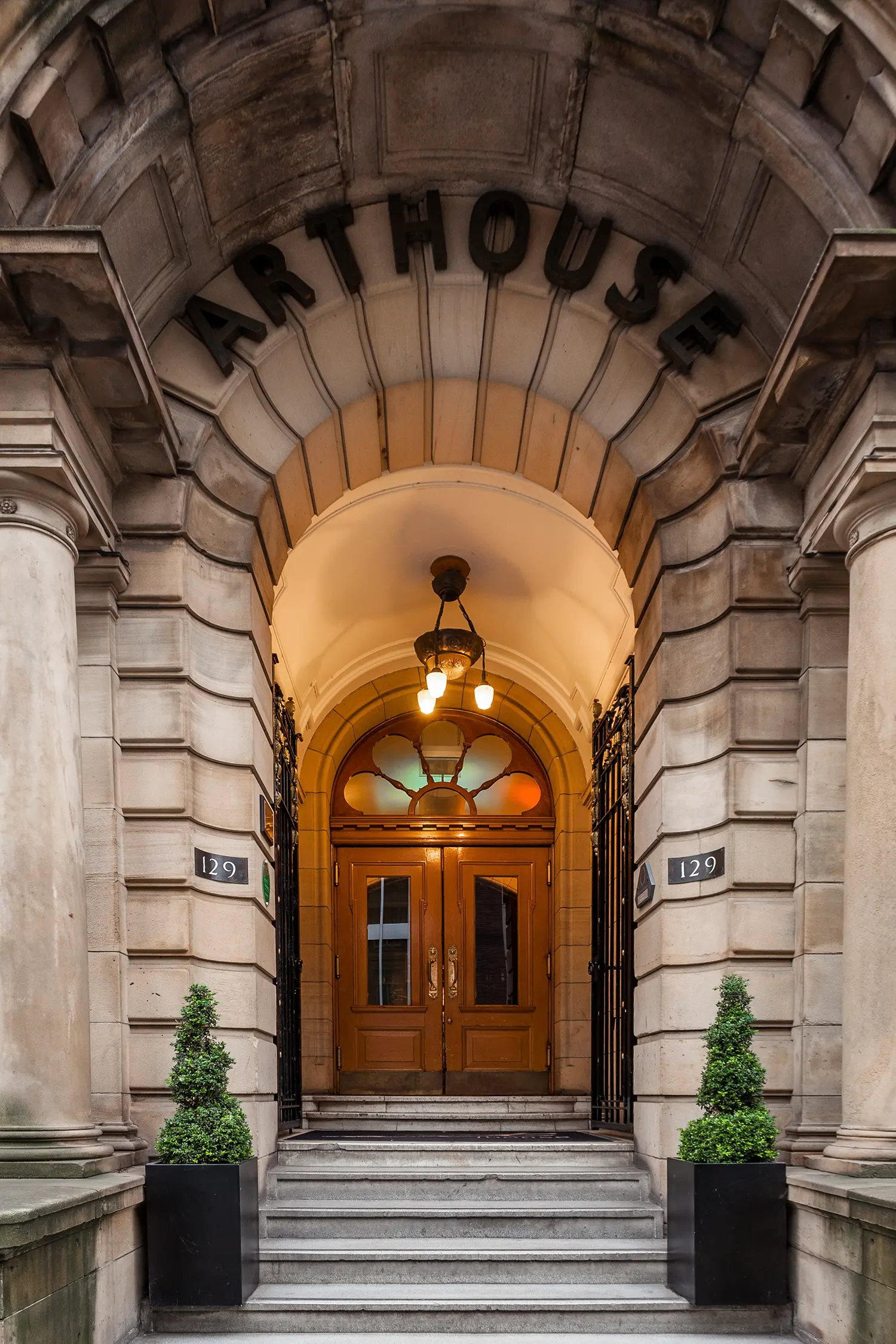 Grand arched stone entrance of Arthouse Glasgow hotel with carved lettering.