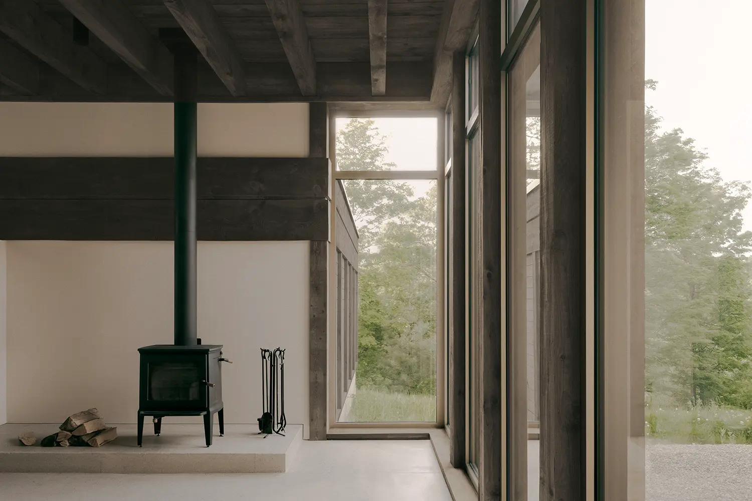 Atelier Carle SONO Residence cast iron wood stove white plaster wall floor-to-ceiling glazing concrete floor Quebec 2025