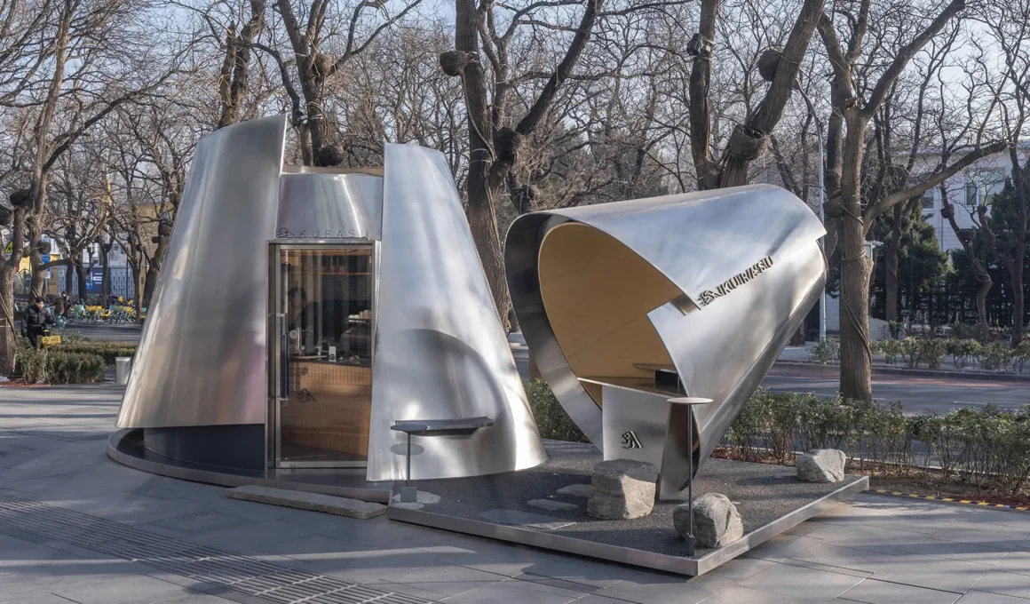 Exterior wide shot of the Kurasu pop-up in Beijing, showing two brushed metal volumes on a gravel base.