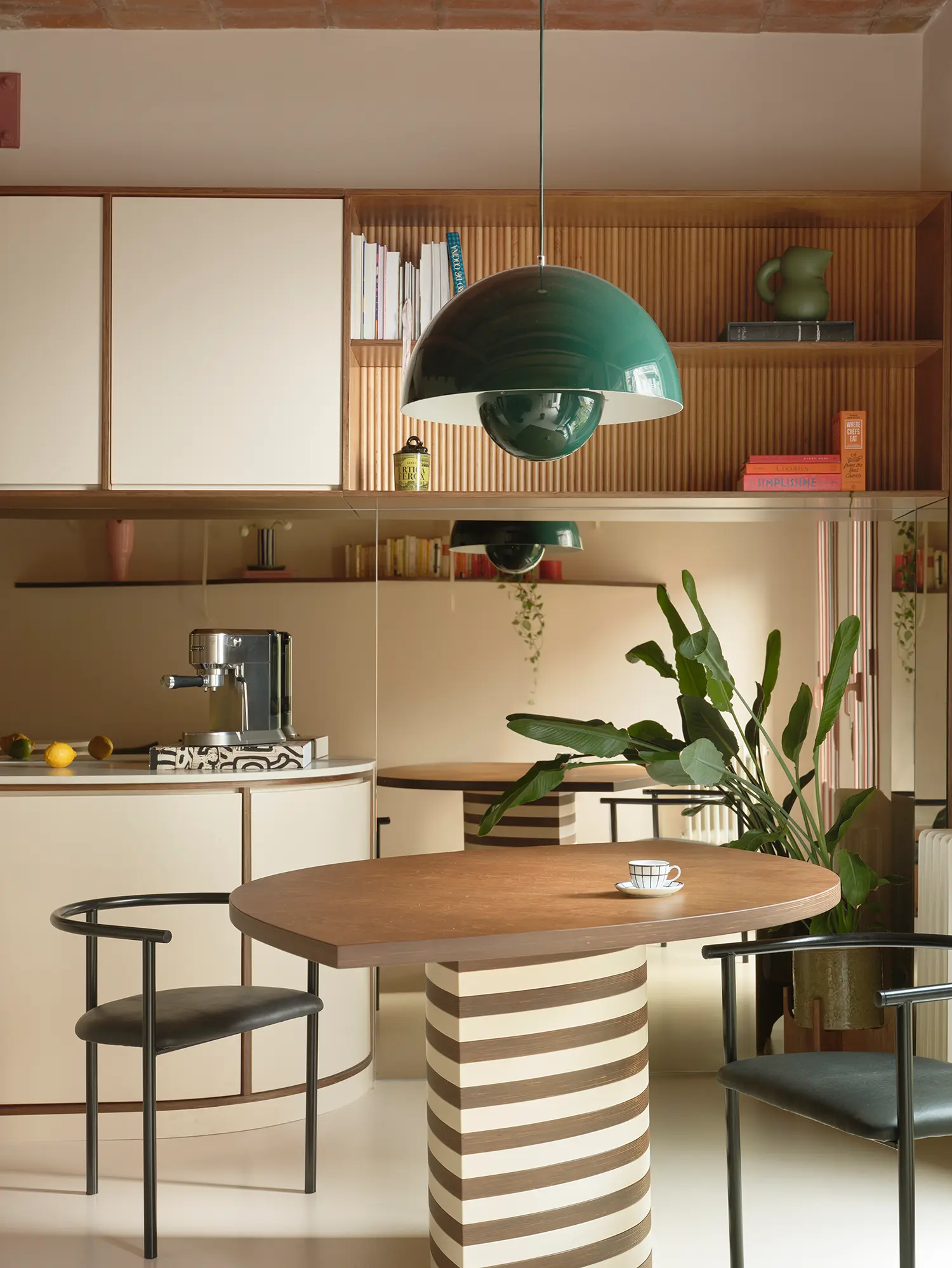 Dining area with a striped cylindrical table base, wooden top, and a forest green Flowerpot pendant lamp.