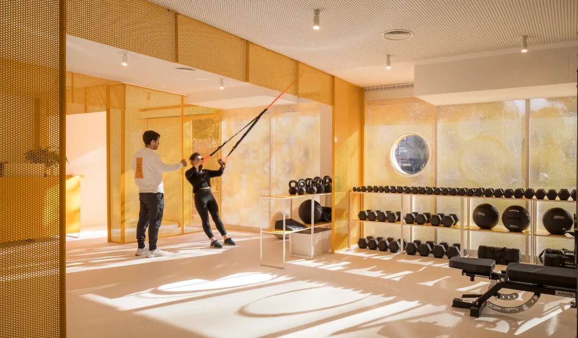 Moof Fitness Studio Madrid by Canobardin, Melongelb RAL 1028 perforated metal screens, floor training zone, dumbbell rack