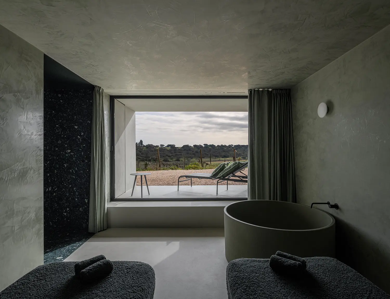 Forest green microcement spa bathroom with circular tub and panoramic landscape window, M Wellness Spa Herdade da Malhadinha Nova, Aires Mateus & Associados