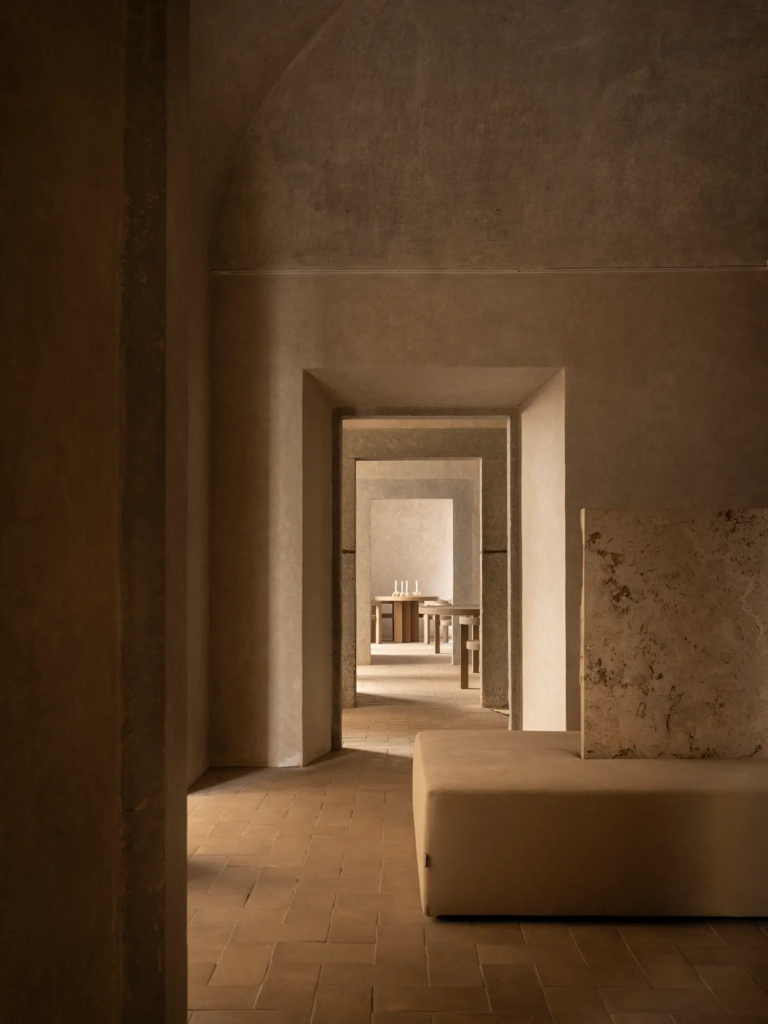 Perspective view through a series of arched stone doorways in a minimalist hotel interior in Rome.