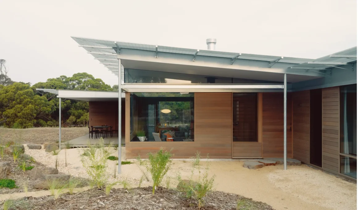 Exterior view of Ironbark House showing the ironbark timber cladding and galvanized steel columns under a wide metal roof.