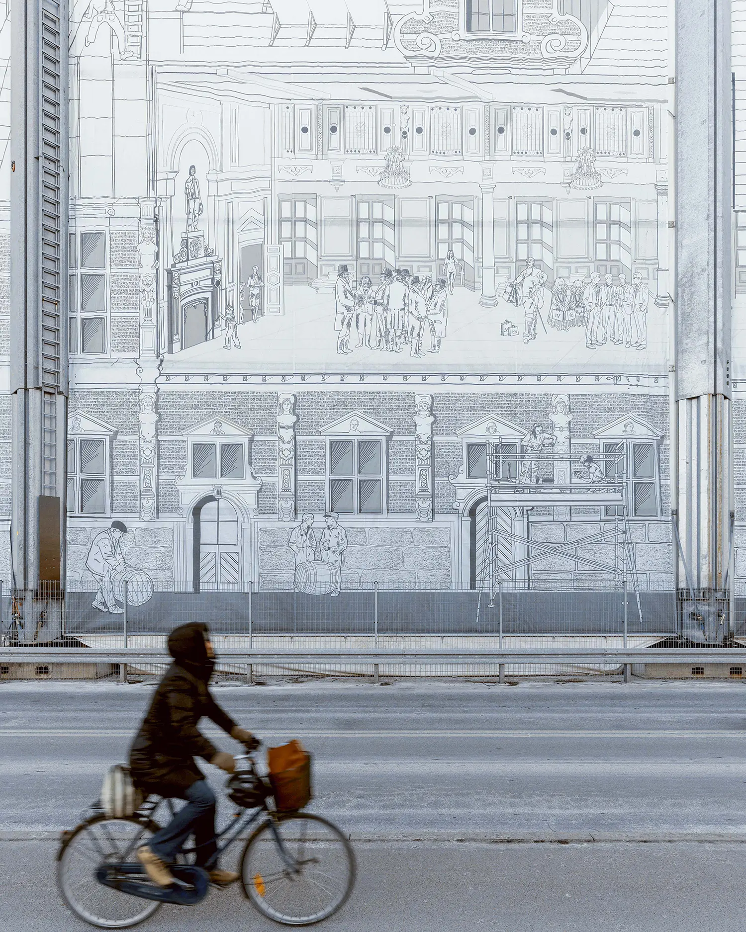 Vertical shot of a cyclist passing in front of a giant hand-drawn illustration on the Børsen construction wrap in Copenhagen.