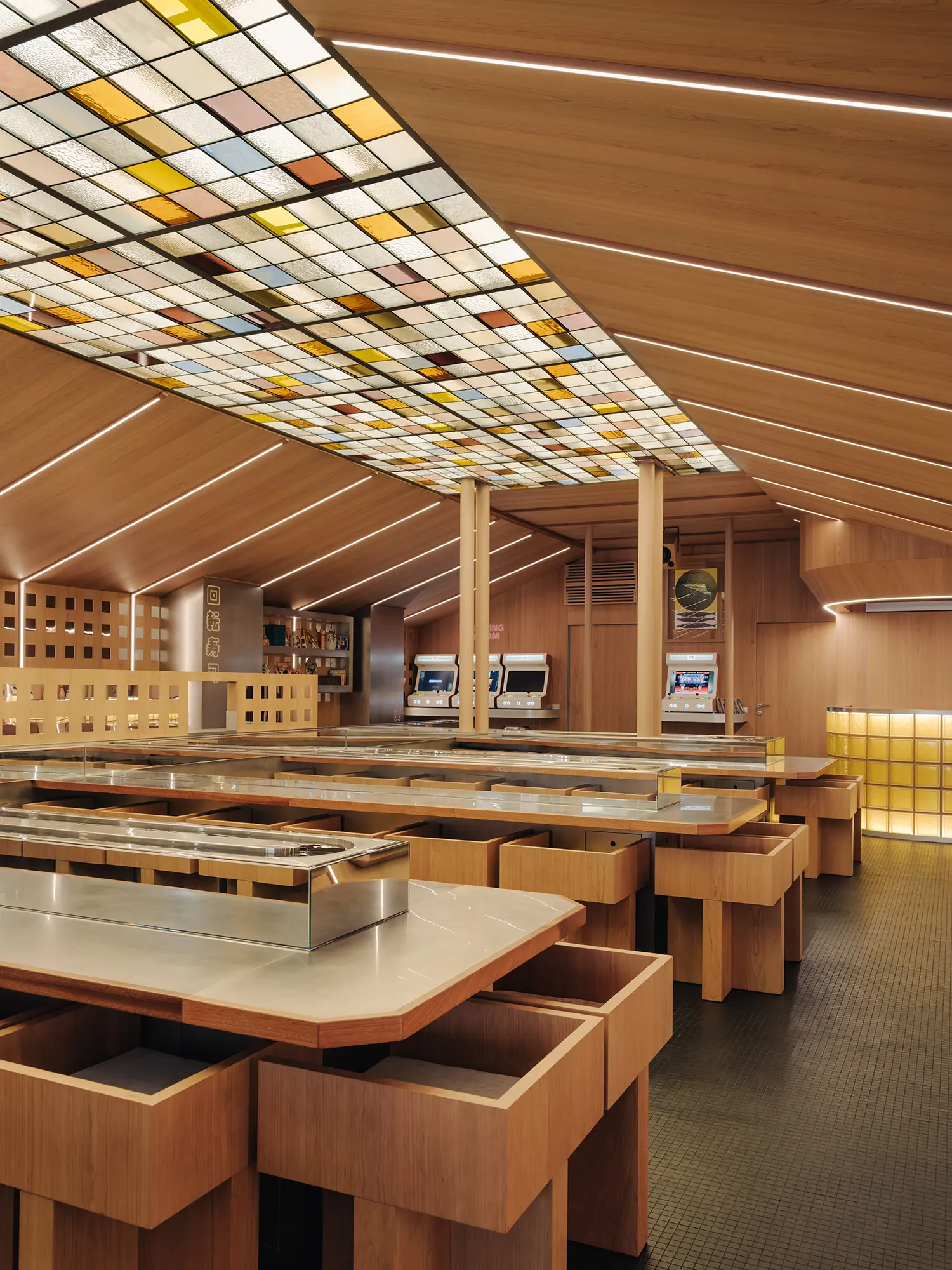 Interior of Matsuri Marseille showcasing the spatial layout with double-sided kaiten conveyor belts, wooden dining counters, and vintage arcade cabinets.