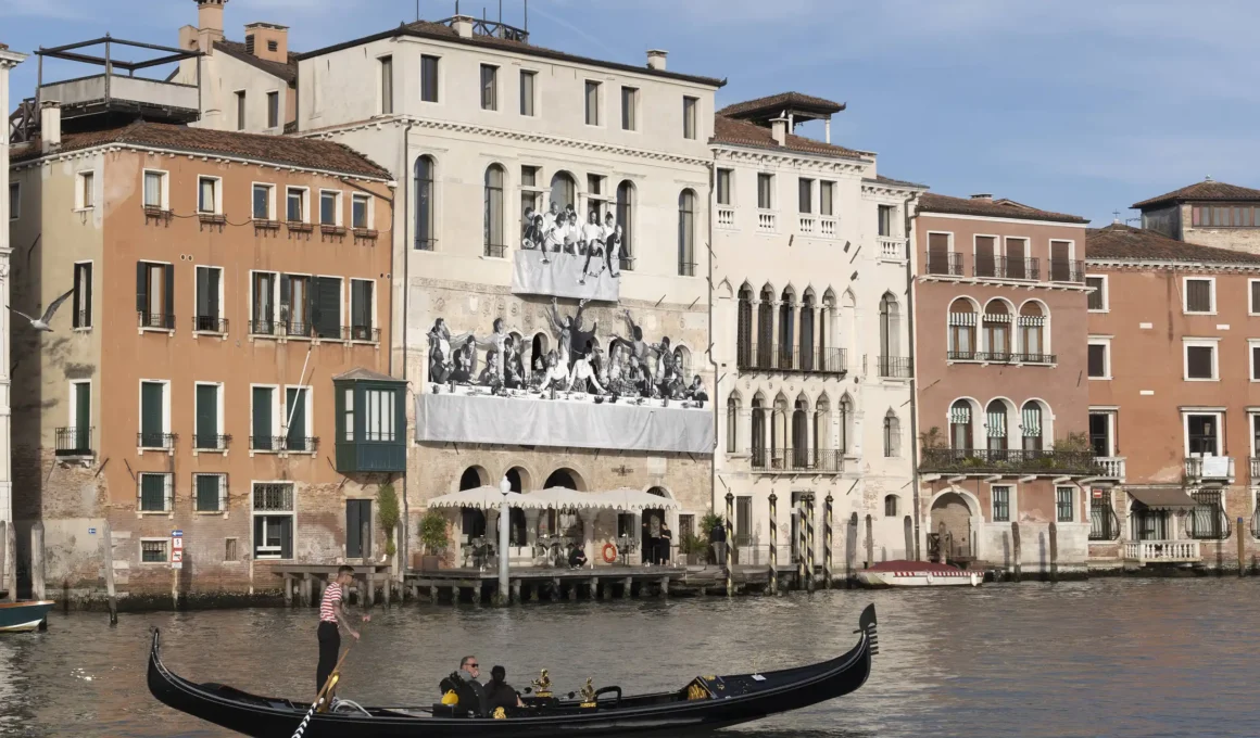 Wide shot of Palazzo Ca' da Mosto in Venice with JR's Il Gesto facade installation visible from the Grand Canal.