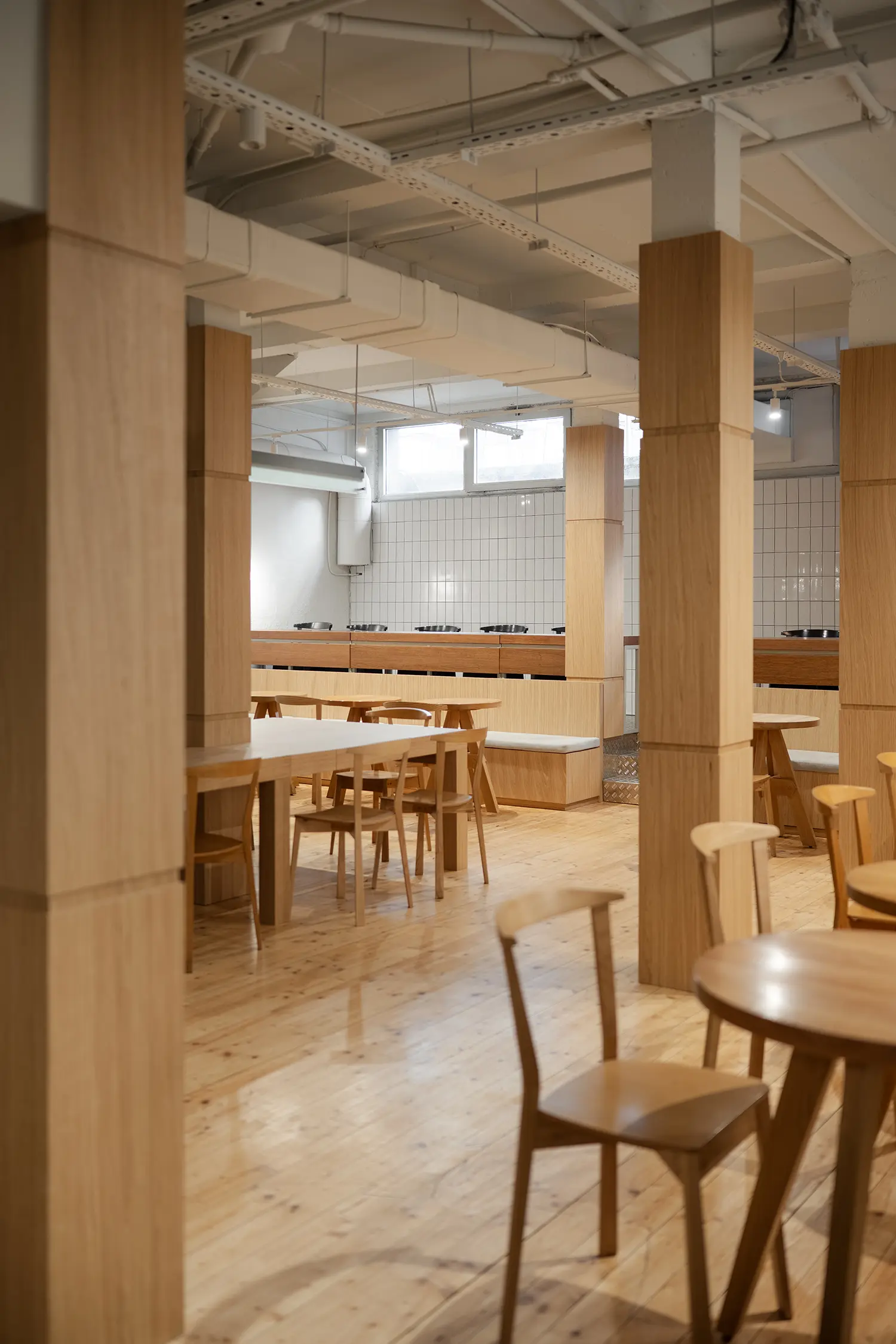Spacious cafe interior with prominent oak columns and light wood flooring.