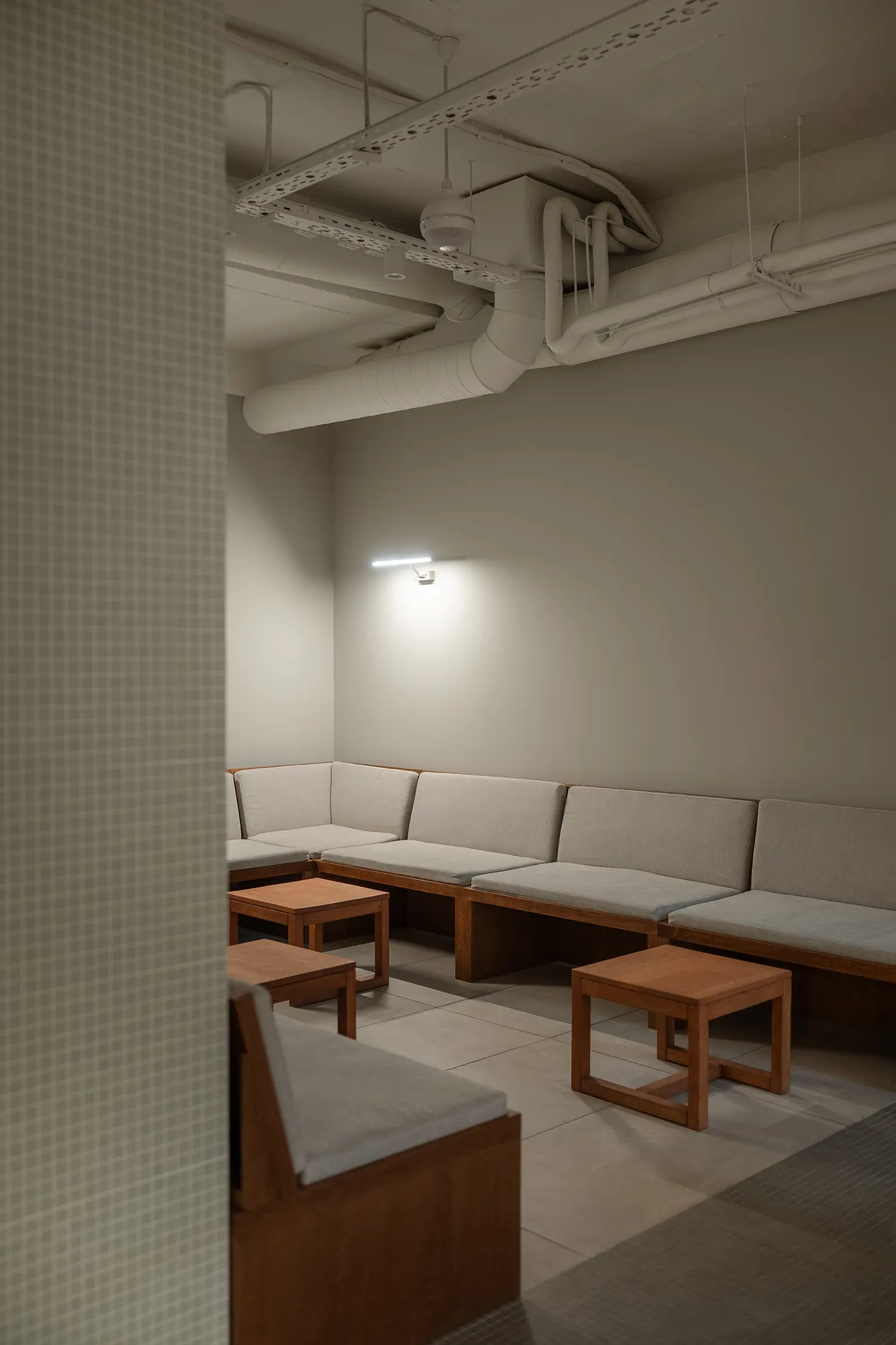 A cozy corner seating area with built-in wooden benches and gray upholstered cushions.