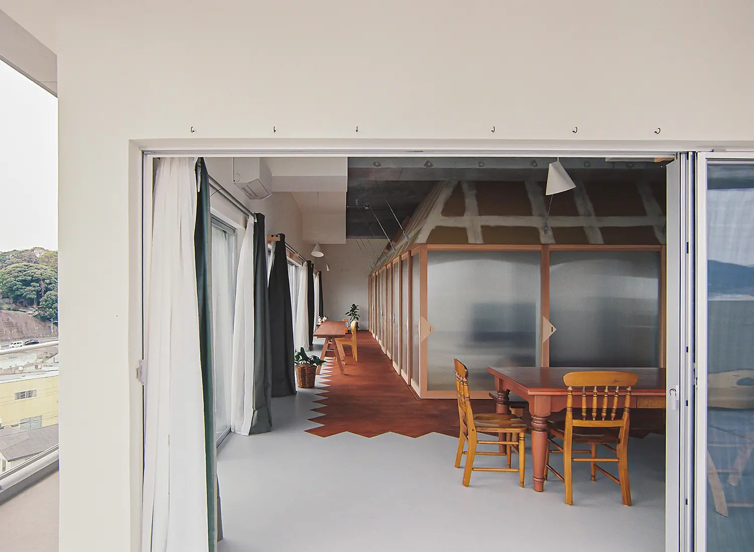 Nakano House Fukuoka by Kuma&Elsa, view from balcony into engawa and dining zone, zigzag timber floor, curtains