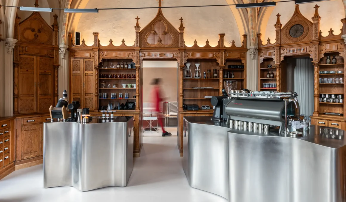 Symmetrical view of Laboratorium specialty coffee shop showing curved stainless steel bars against neo-Gothic wooden cabinetry.