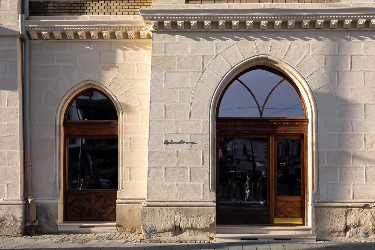 Exterior facade of Palatul Széki showing the stone ogival arches and minimalist Laboratorium signage.