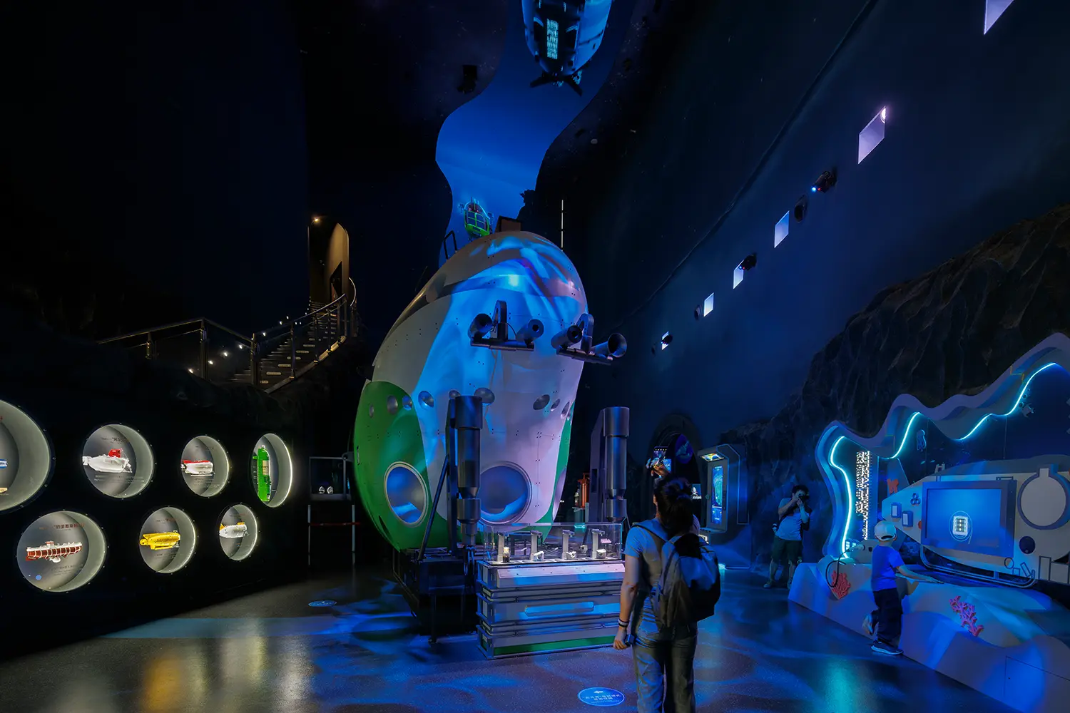Exhibition space featuring a large green and white submersible model and interactive scientific displays.