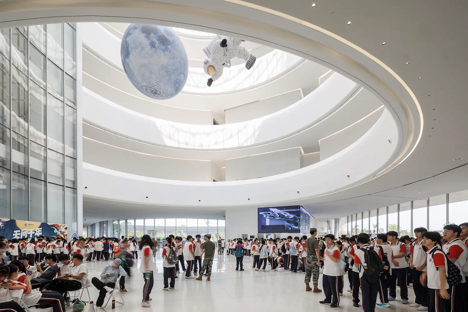 Large white atrium with spiraling ramps and a suspended model of the moon and an astronaut.