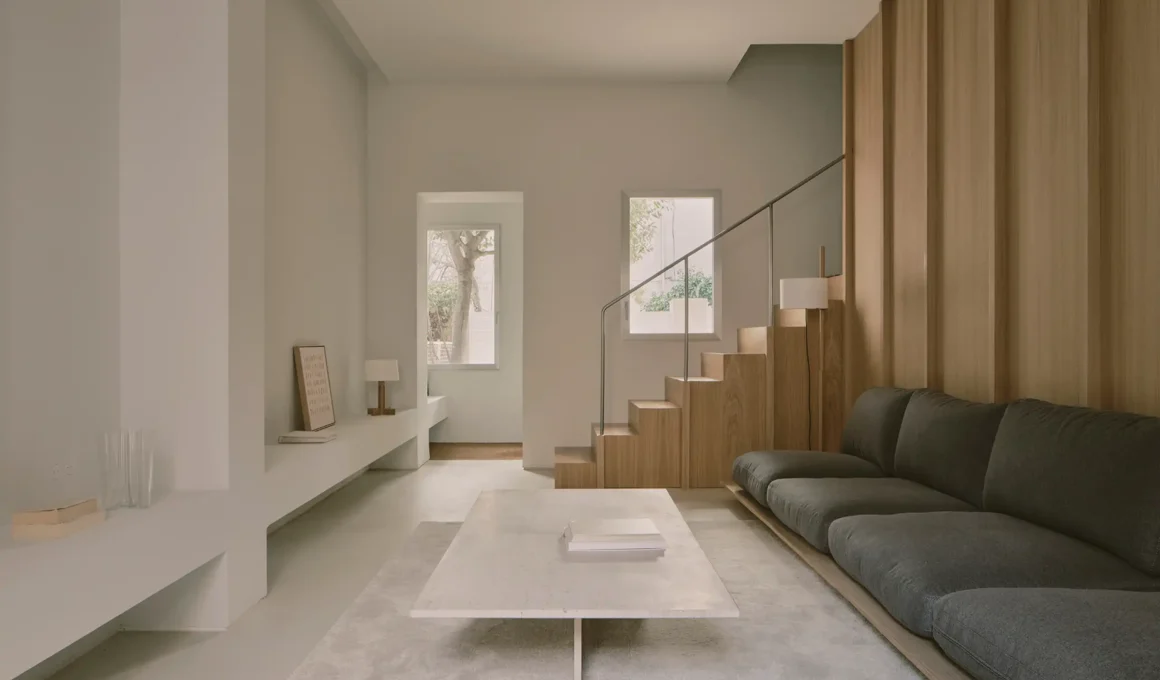 Minimalist living room with a gray sofa, marble coffee table, and oak-clad staircase.