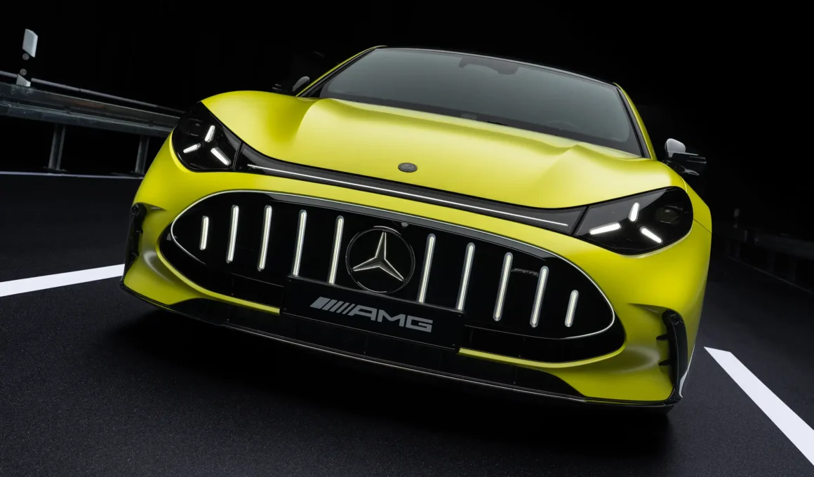 Three-quarter front view of a copper-orange Mercedes-AMG GT 4-Door Coupé parked on an asphalt coastal road at sunset.