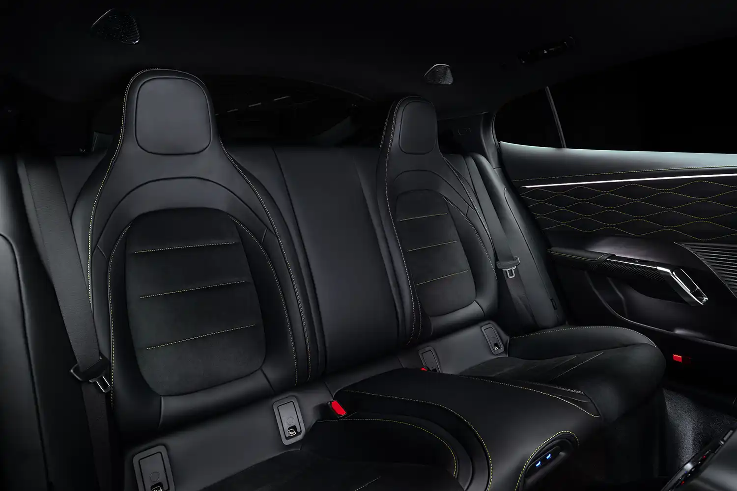Interior shot focusing on sculpted black leather sports seats with integrated headrests and contrasting neon yellow stitching.
