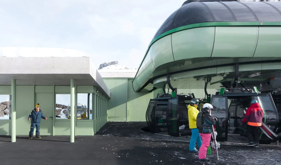 Lezuo Belvedere Mimeus Architettura — gondola boarding area with light green expanded metal cladding, exposed concrete canopy, skiers at valley station