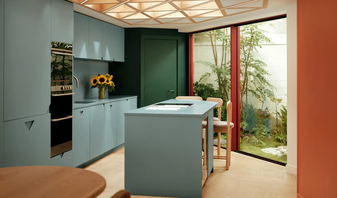 Kitchen with pale blue cabinetry, tessellated glulam rooflight, green accent wall, and glazed courtyard view, Moon House London