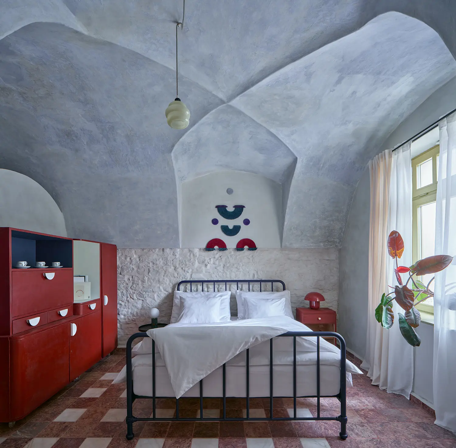 Oblouková 171 ORA — vaulted bedroom with hand-applied lime plaster ceiling, salvaged red marble floor tiles, iron bed frame, exposed stone wall