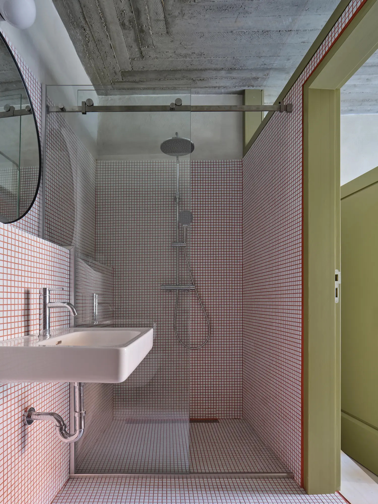 Oblouková 171 ORA — bathroom with full small-grid mosaic tile surround, exposed concrete slab ceiling, olive-green panelled door surround