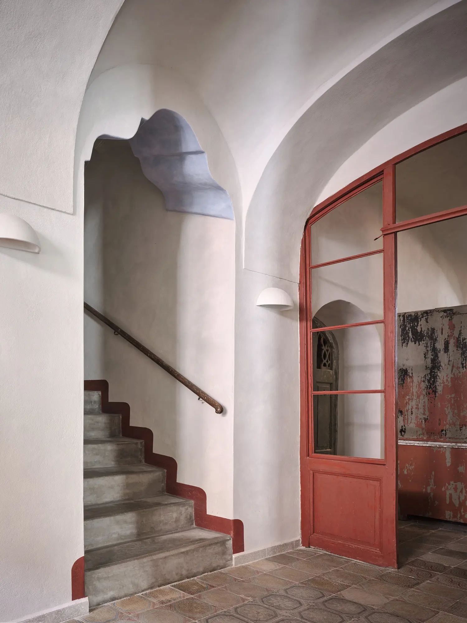Oblouková 171 ORA — entrance passageway with lime-plastered barrel vaults, salvaged South Bohemian farmstead floor tiles, original red-painted glazed door
