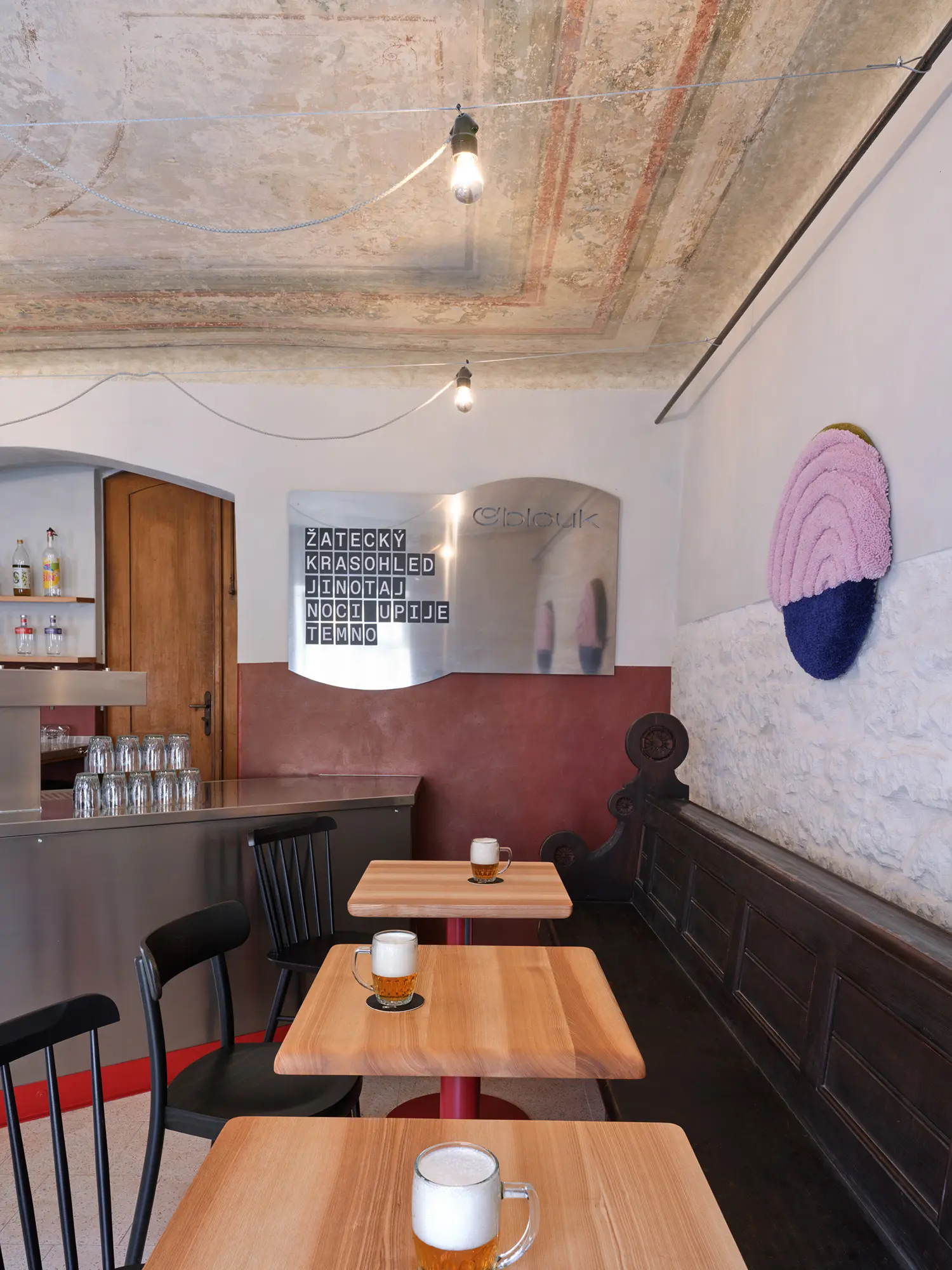 Oblouková 171 ORA — FALKON taproom interior with exposed fresco ceiling, polished steel bar counter, original dark timber bench panelling