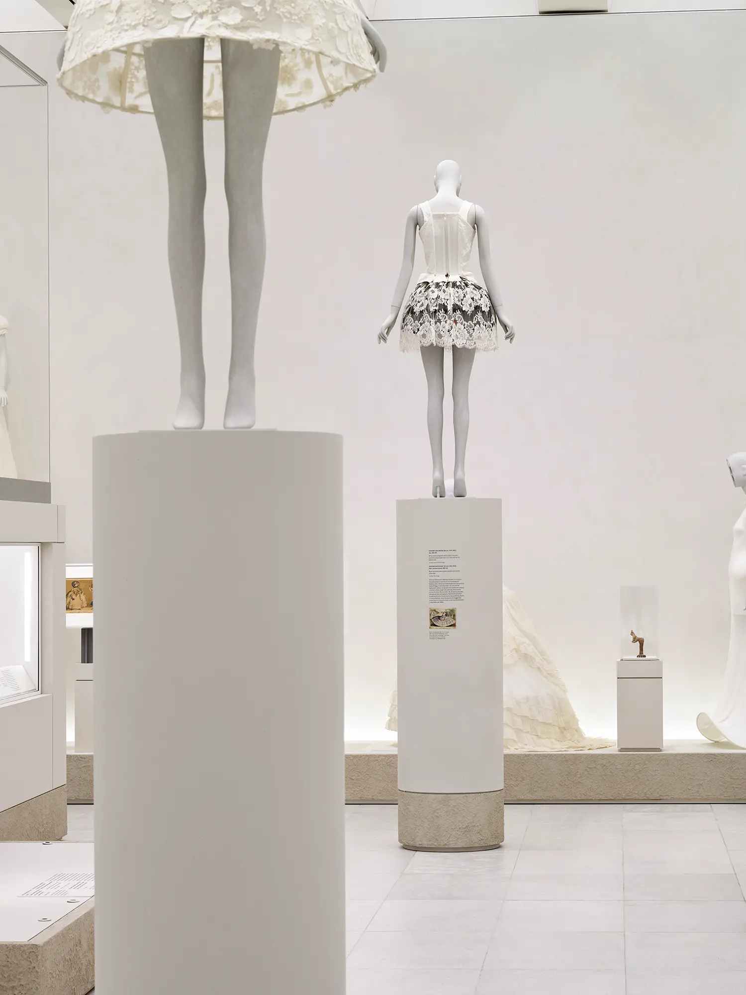 Minimalist museum gallery entrance showing massive double-leaf oak doors open to a brightly illuminated high ceiling exhibition hall.