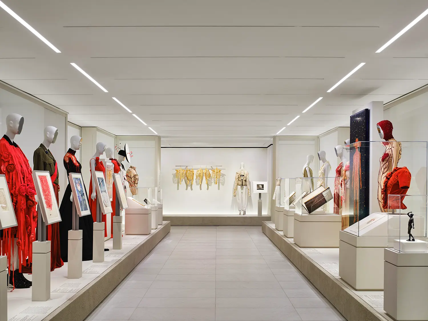 Tall rectangular window opening in a grey plaster wall looking into a brightly illuminated neighboring gallery with classical artifacts.