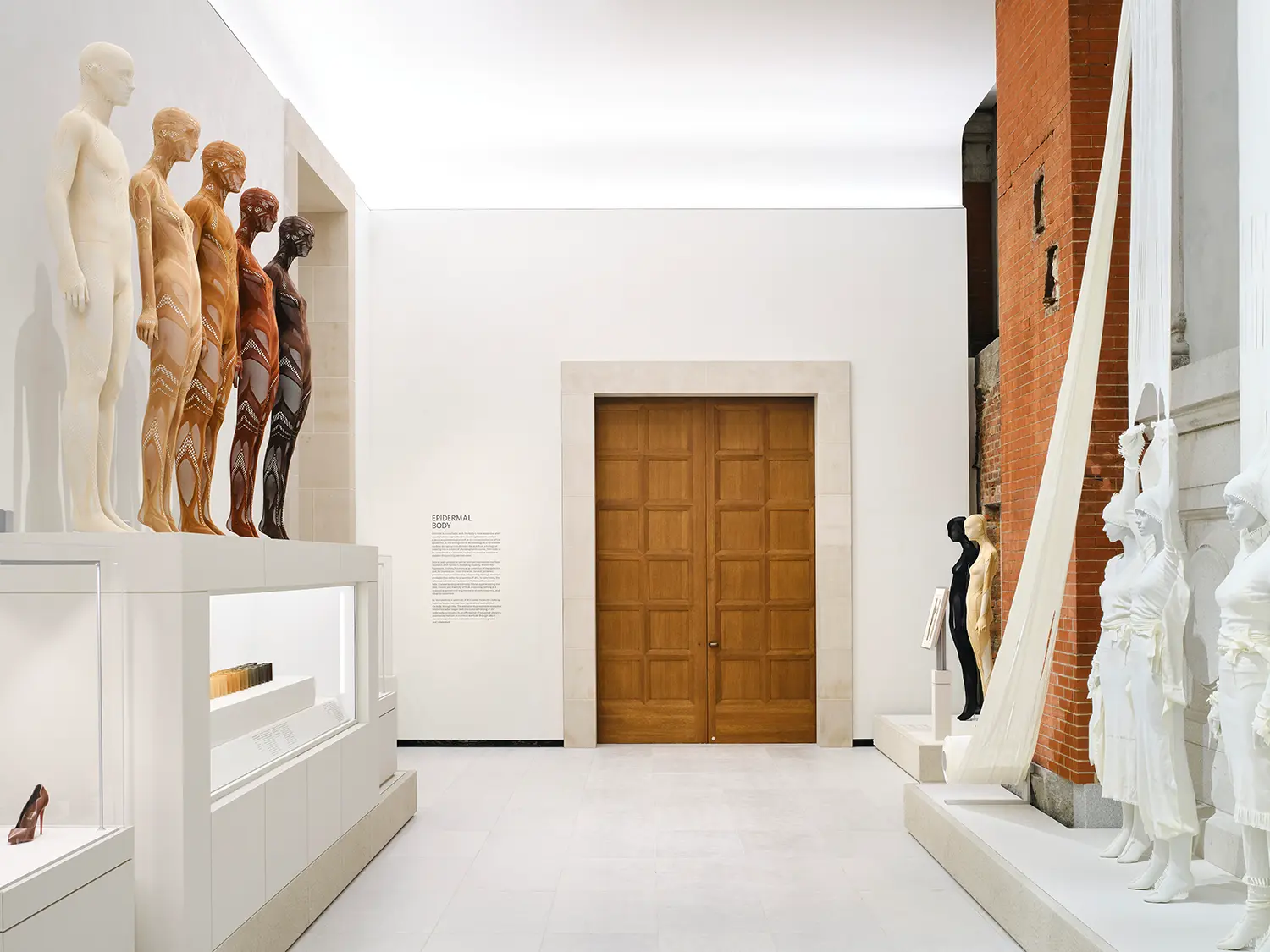 Detailed view of exposed historic red brickwork and mortar joints adjacent to a smooth, neutral modern museum gallery wall.