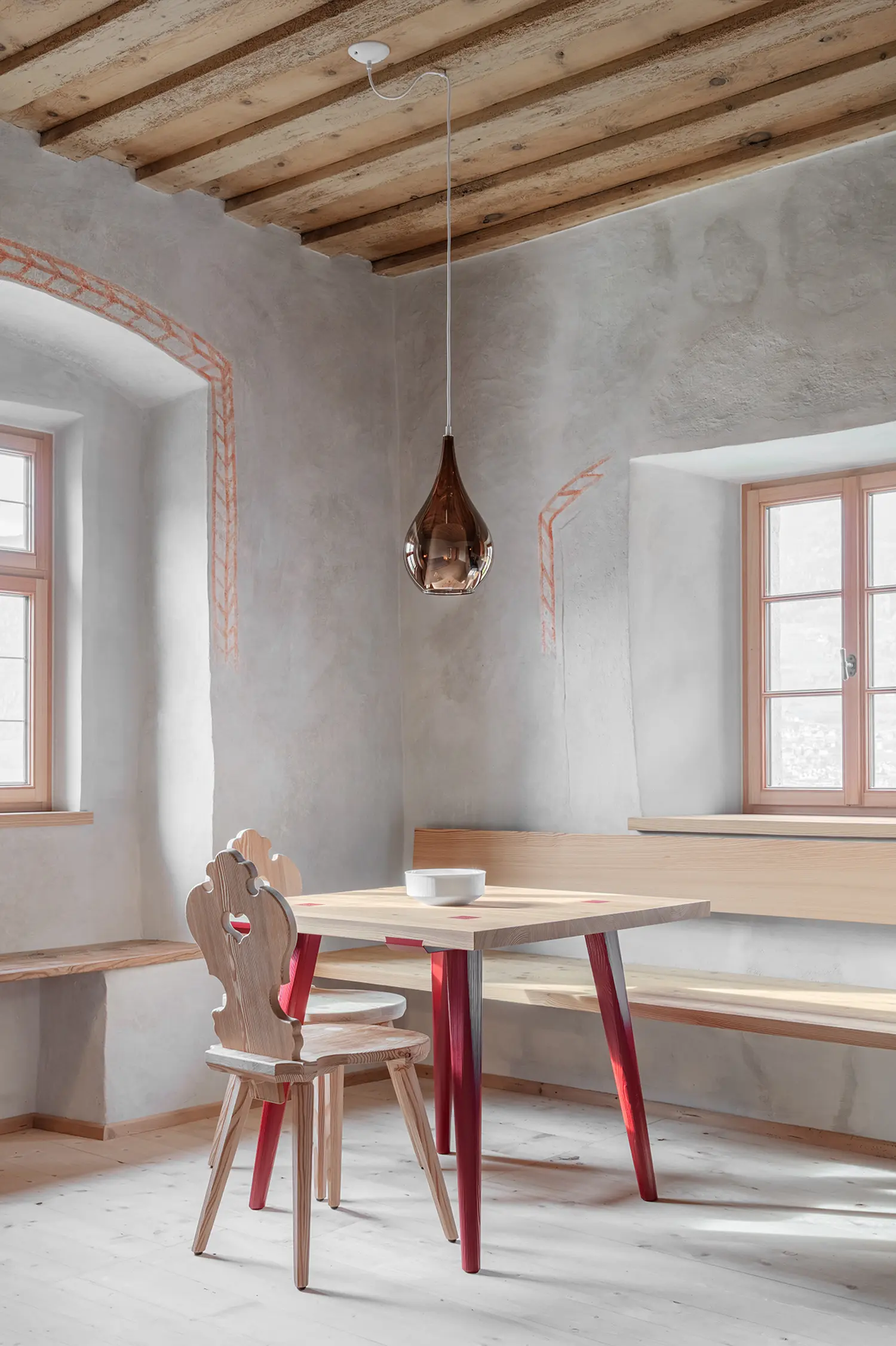 Dining area with a light wood table, traditional carved wooden chairs, and a modern glass pendant light.