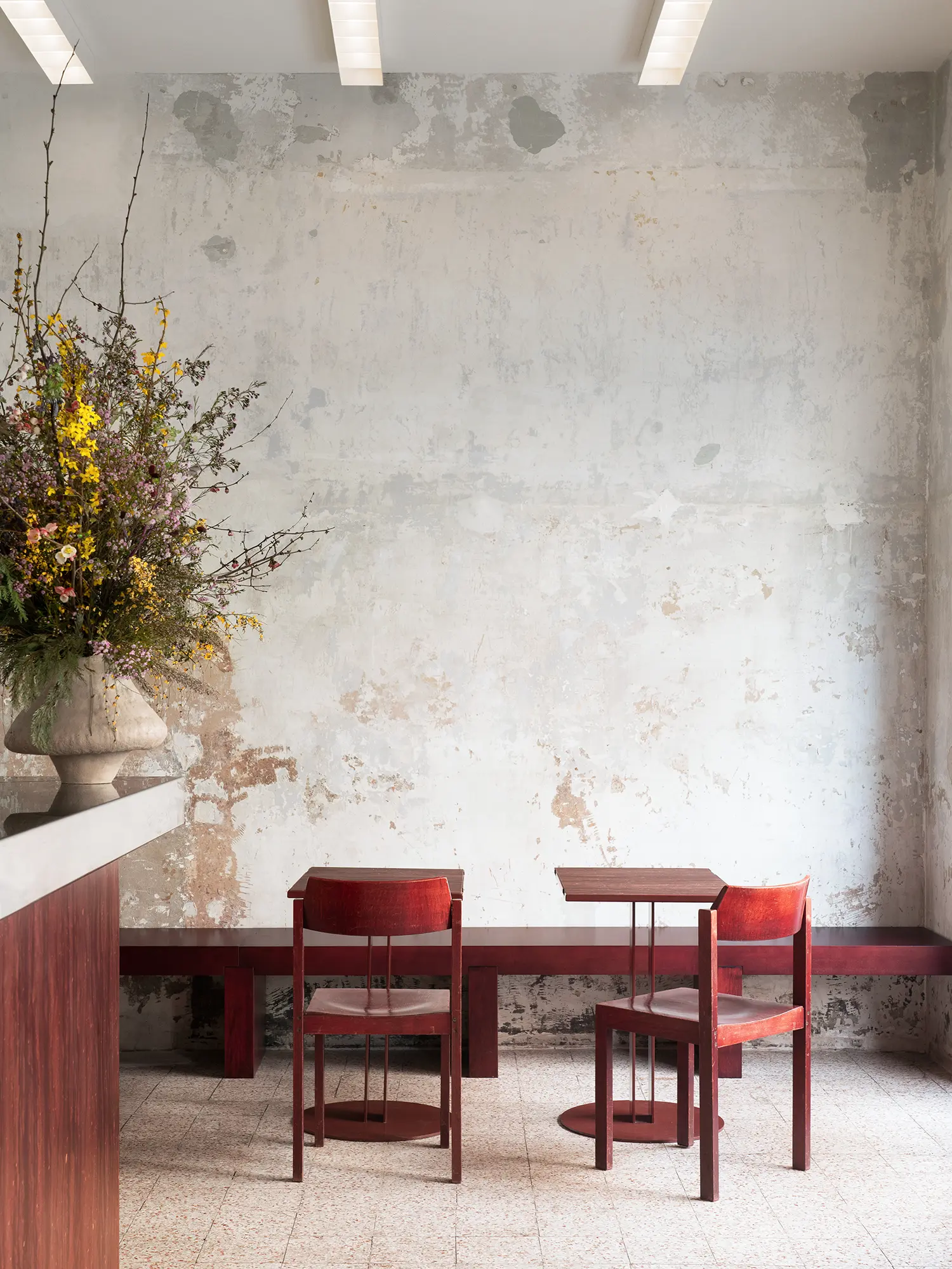 Interior shot of Bar Rito showing stripped white walls, vintage red chairs, and restored terrazzo flooring.