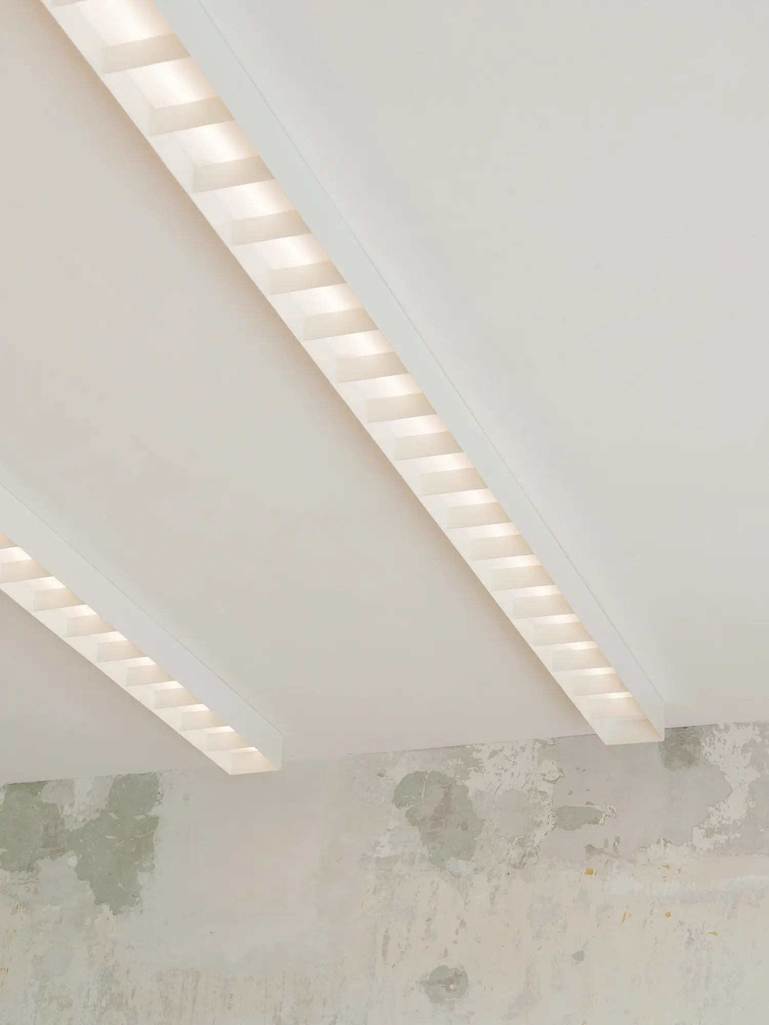 Low angle view of custom white linear ceiling lights with opaline diffusers.