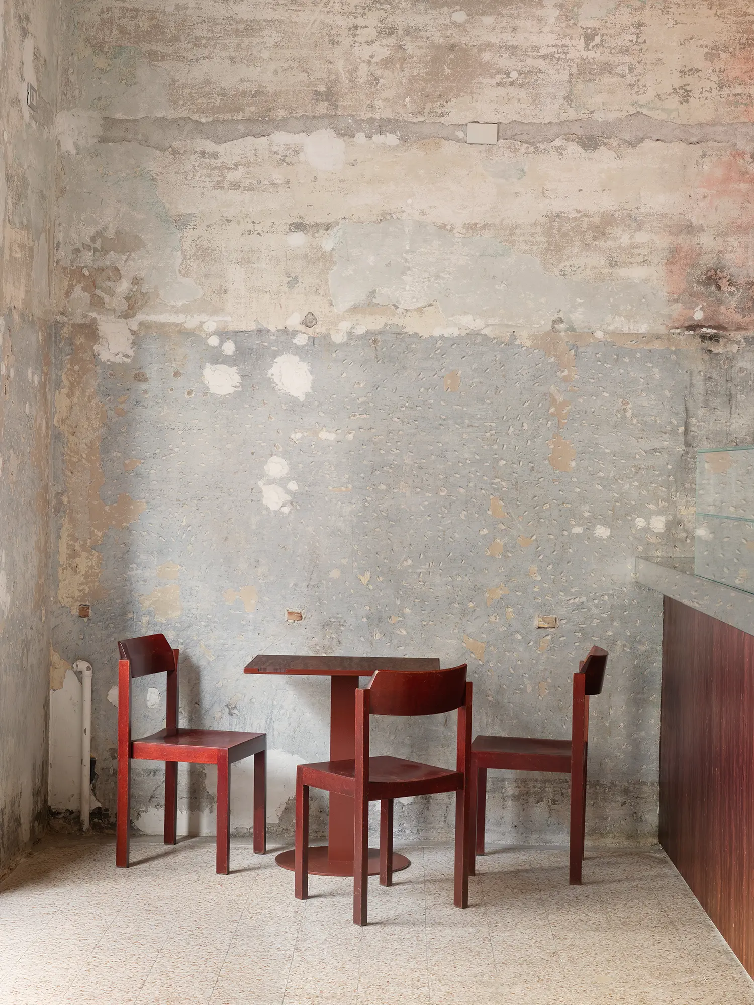 Wide interior shot of a dining corner with two red chairs and a custom table against a two-tone stripped wall.