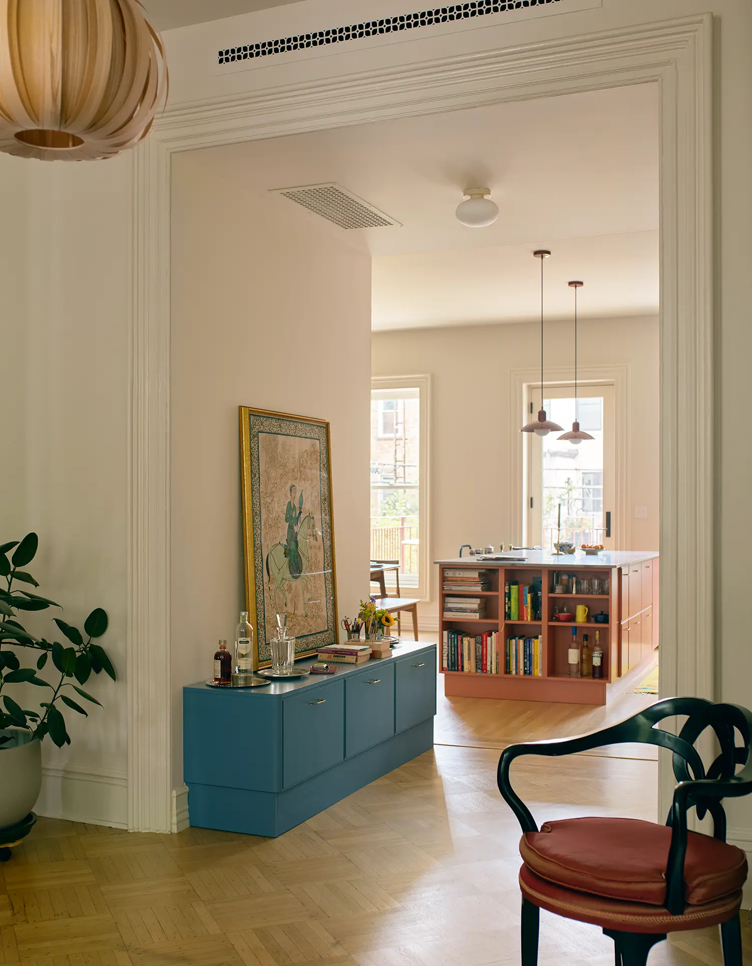 Open floor plan view from a white-walled room with a blue console toward the kitchen area with a terracotta island.
