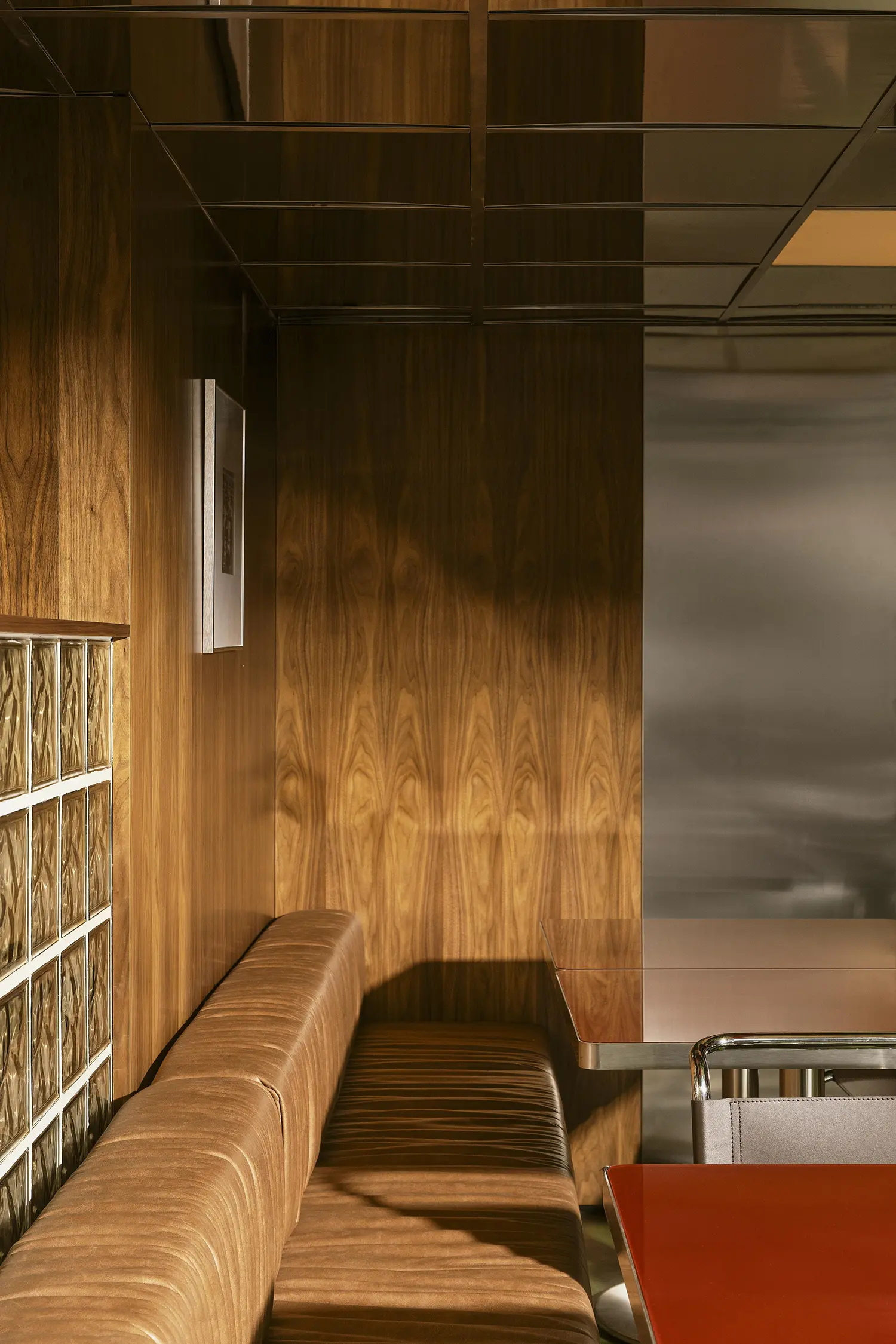 Close-up of leather seating, high-gloss red tables, and a glass block wall section.
