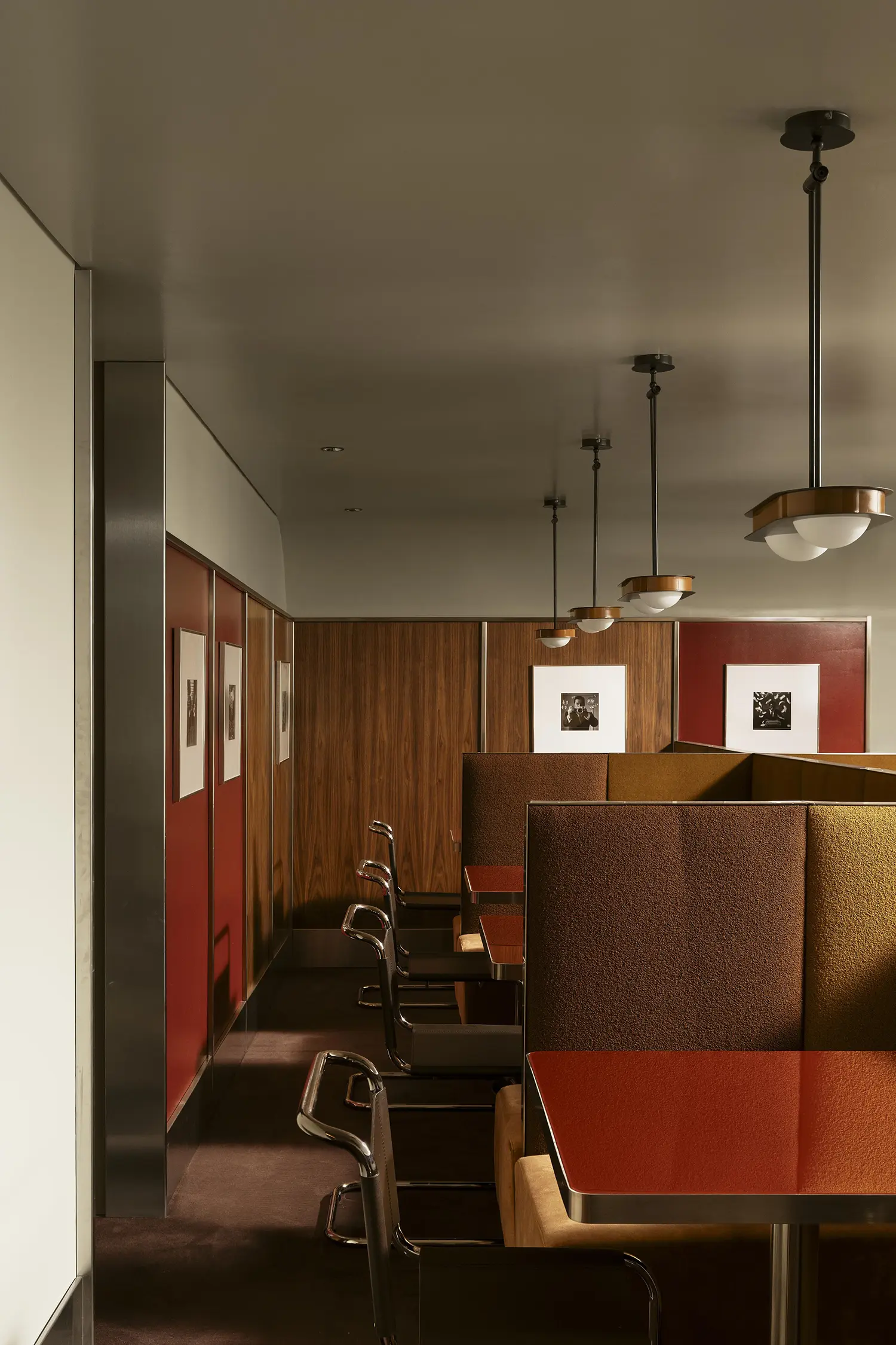 The mezzanine lounge layout featuring brown and yellow bouclé-covered privacy booths and retro pendant lamps.