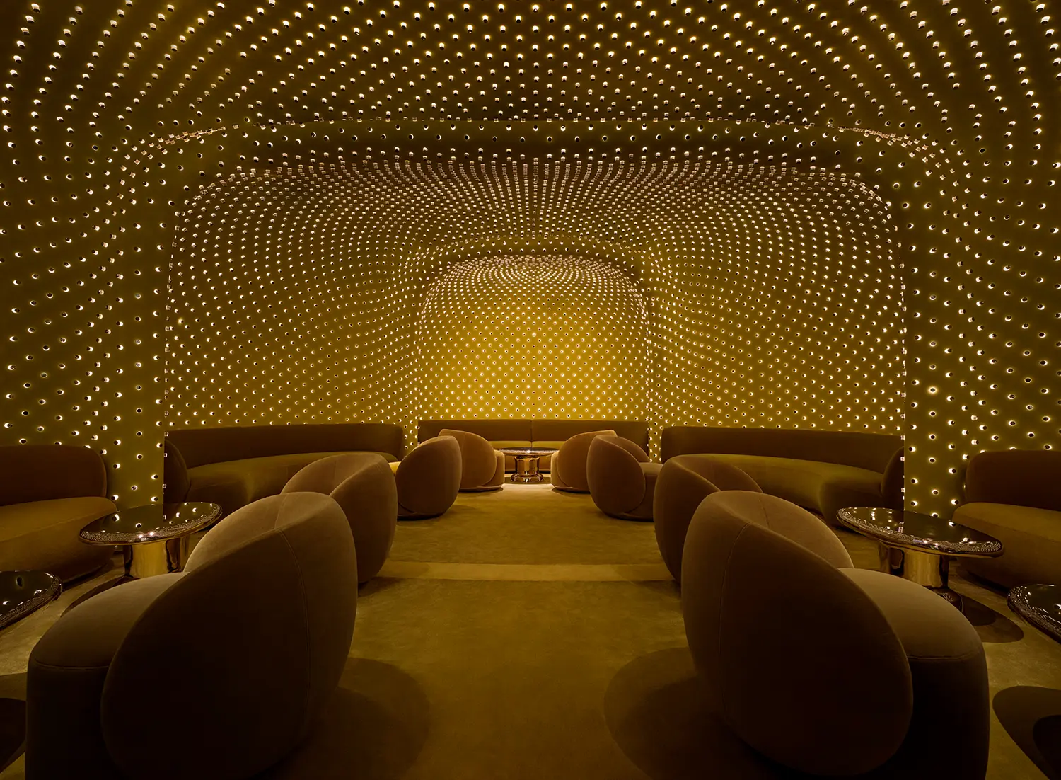 Symmetrical view of a green lounge area with a curved ceiling covered in a matrix of small glowing light fixtures.