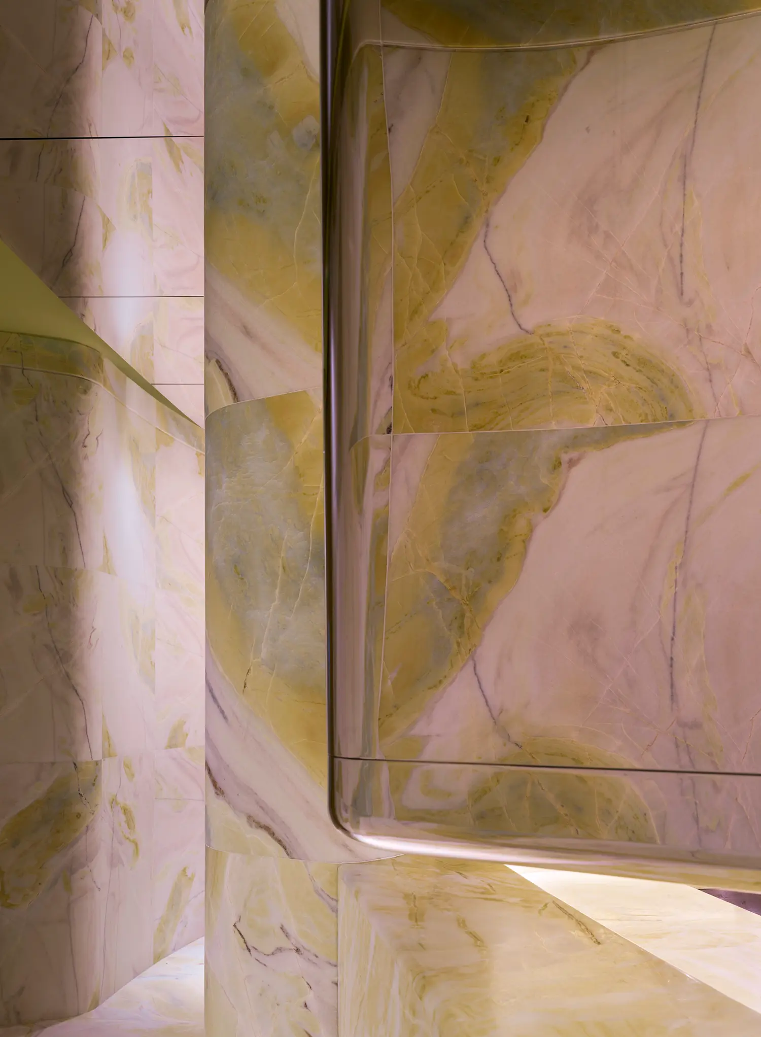 Abstract detail of curved green marble walls and polished metal trim in Peridot bar.